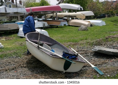 man pulling row boat on ground