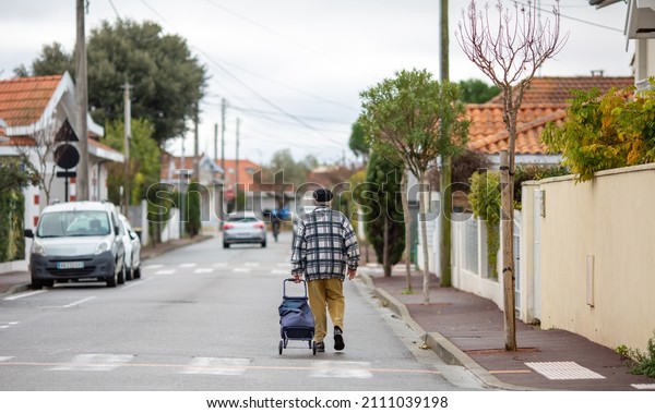 Man pulling a shopping\
bag on wheels
