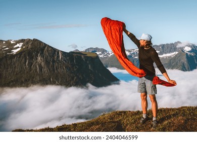 Man pulling sleeping bag out of its cover hiking camping gear active travel vacations in mountains outdoor, traveler exploring Norway adventure sustainable tourism  - Powered by Shutterstock