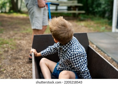 A Man Pulling A Wooden Wagon With His Son.