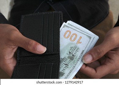 a man pulls cash from his wallet that shows one hundred dollar bill. - Shutterstock ID 1279142917