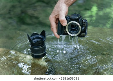 man pulls his digital camera out of the river that has accidentally fallen into the river flooded from inside
