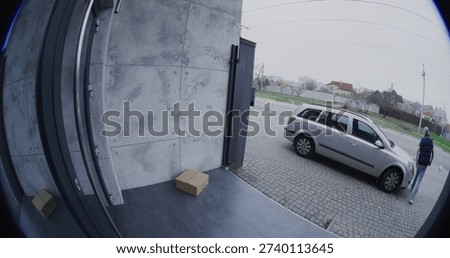 Man Pulls Up in Silver Car. Courier Retrieves Large Parcel, and Carelessly Throws it Onto Porch. Negligent Delivery Captured by Smart Doorbell Camera. Concept of Poor Service and Property Security.