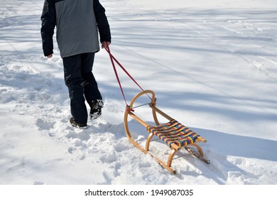 A Man Pulls A Sledge Up A Hill In The Winter Tobogganing