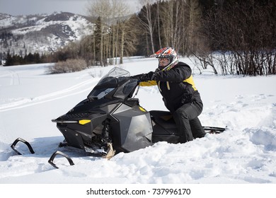 A Man Pulls A Snowmobile Stuck In The Snow