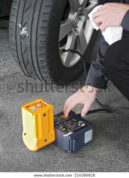 Man\
pumping a car tire with electrical compressor\
