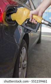 Man Is Pumping Gas In Black Car In Fuel Station.