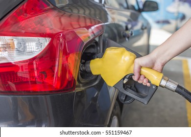 Man Is Pumping Gas In Black Car In Fuel Station.