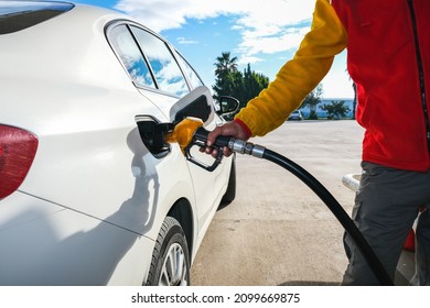 Man pumping gasoline fuel in car at gas station and being fill gas tank of white car in gas station, Concept of Global Fossil Fuel Consumption, Rising gasoline prices, Copy Space.