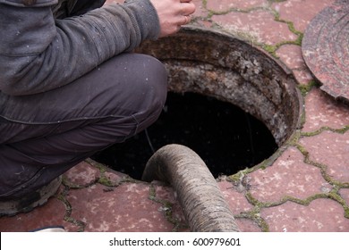 Man Pumping Sewage From The Drain Hole