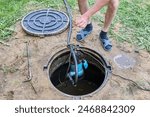 Man pumps wastewater out of the septic tank using submersible sump pump.