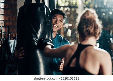 Man, punching bag and smile in gym, personal trainer and practice with instructor, energy and boxing. Health club, sports and endurance of boxer, people and wellness of workout or exercise in morning - Powered by Shutterstock