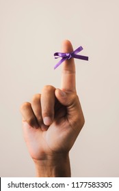 Man With A Purple Ribbon Tied To His Forefinger, For The World Alzheimers Day, On An Off-white Background