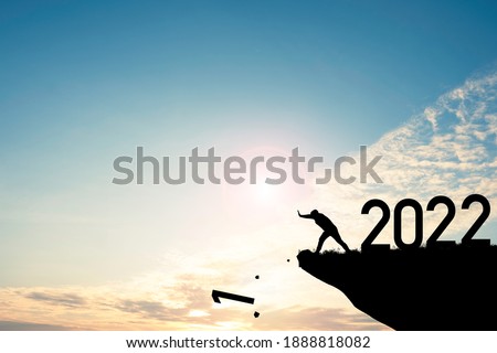 Man push number one down the cliff where has the number 2022 with blue sky and sunrise. It is symbol of starting and welcome happy new year 2022.