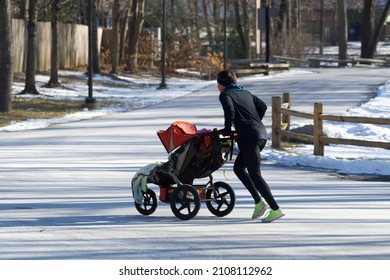 A Man Pushes A Stroller In Front Of Him While Out Running In The Park