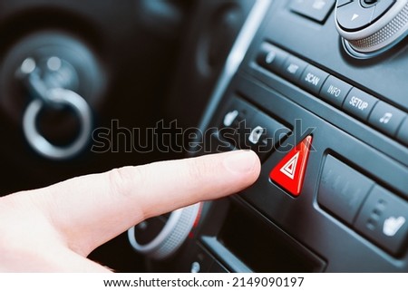 Man pushes a triangle emergency button on car dashboard. Close up view with shallow depth of field.