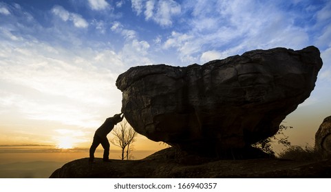 Man pushing a boulder on a rock 