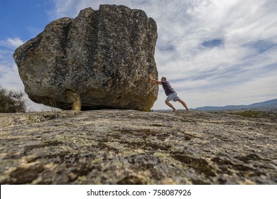 Man pushing a boulder on a rock
