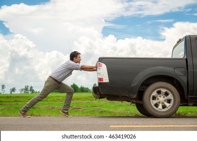 Man pushing a broken car down the road - Shutterstock ID 463419026