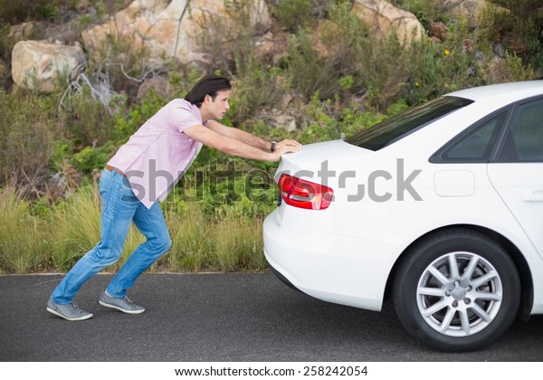 Man pushing car after a car breakdown at the side of\
the road