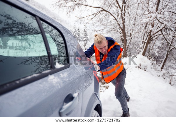 Man pushing car at winter day\

