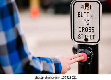 A man pushing a crosswalk button that reads, 