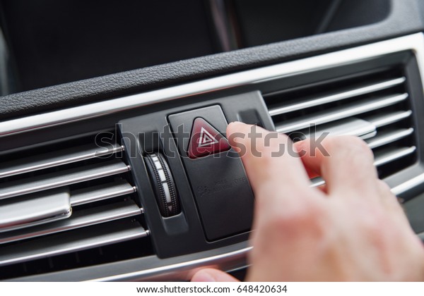Man pushing emergency light button while driving\
car. emergency stop.