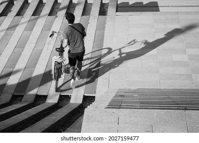 A Man Pushing His Bicycle Outdoors In Bercy Park