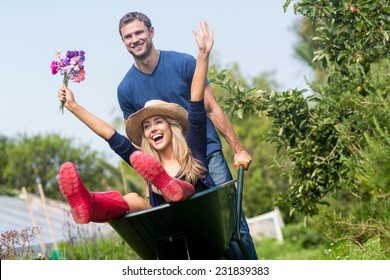 Man pushing his girlfriend in a wheelbarrow at home in the garden - Powered by Shutterstock