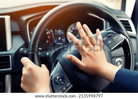 man pushing horn while driving sitting of a steering wheel press car, honking sound to warn other people in traffic concept.