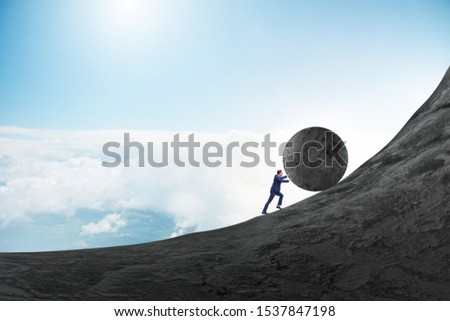 Man pushing large stone to the top