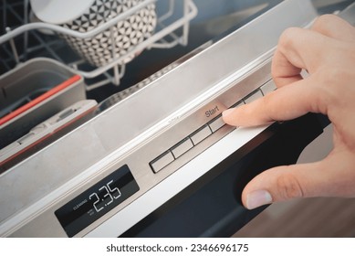 Man pushing start button on the control panel of the dishwasher.