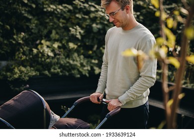 Man Pushing Stroller Outdoors. Father With Baby In Pram.