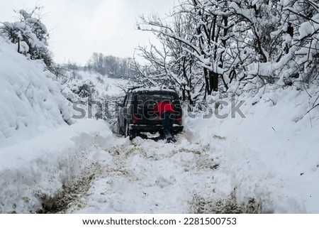 Man pushing the stuck vehicle in the snow