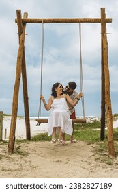 Man pushing woman on a swing at the beach