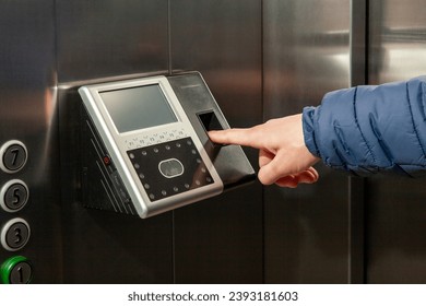 The man put his finger in the Fingerprint Access Control Terminal with face recognition function installed in the elevator of the business center, which tracks attendance in real time