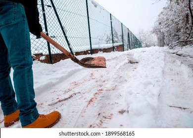 Man put salt on snowy driveway to protect from slippery. Winter snow cleaning outside. Applying Rock Salt ( Gritting ) to an Icy Path - Shutterstock ID 1899568165
