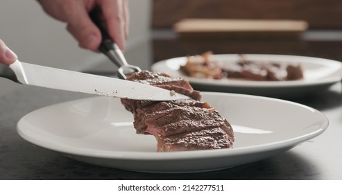 Man Put Sliced Ribeye Steak On A White Plate On Concrete Countertop