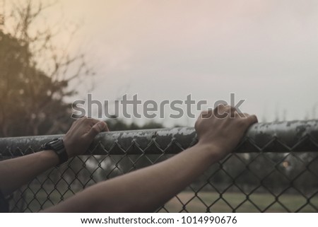 man put two hand on steel fence in field,Hopeful,waiting for someone