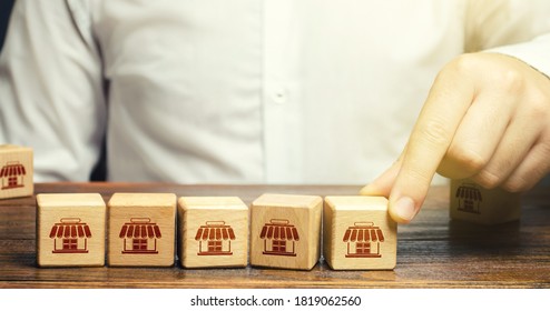Man puts blocks with shop symbols in a row. Building a successful business empire. Franchise concept. Merging competitor, creation of a large network. Commercial association - Shutterstock ID 1819062560