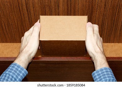 A Man Puts A Cardboard Box High On A Shelf