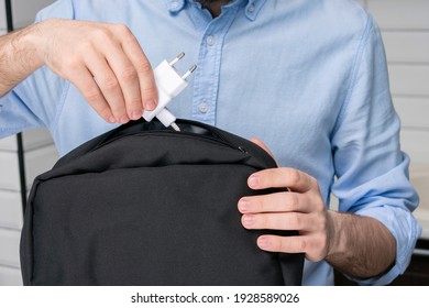 Man puts charger for phone in a backpack, male hands, cropped image, close-up - Shutterstock ID 1928589026