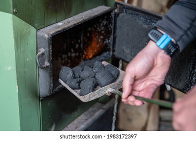 The Man Puts The Coal Into The Stove.