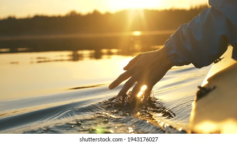 man puts fingers down in lake kayaking against backdrop of golden sunset, unity harmony nature - Powered by Shutterstock