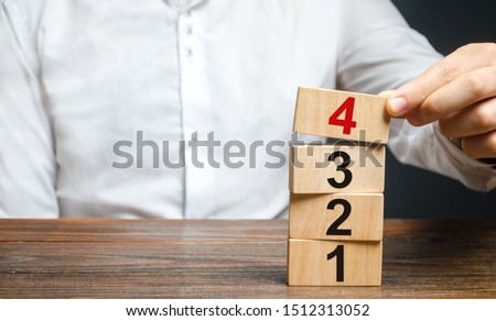 A man puts numbered wooden blocks on top of each other. Alternate items and conditions for implementation. Contract road map. Organization and systematization, step by step instructions.