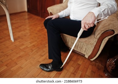 Man puts on classic black shoes with a wooden shoe spoon. - Shutterstock ID 2188606973