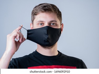 Man puts on a face mask. Black stylish face mask during a pandemic virus crown. Handmade cotton face mask for protection against viruses and bacteria. - Shutterstock ID 1696092910