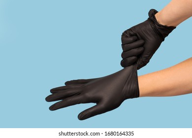 man puts on sterile black gloves on a blue background. Hazard, hygiene