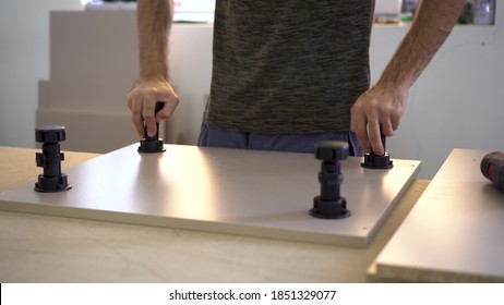 A Man Puts Plugs On Wooden Parts In A Furniture Manufacturing Facility.