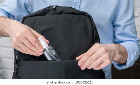 Man puts sanitizer or antiseptic,  in a backpack, male hands, cropped image, close-up - Shutterstock ID 1923625115